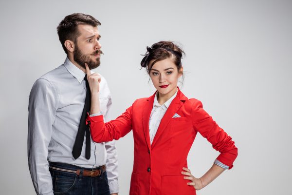 The funny business man and woman communicating on a gray background. Business concept of relationship of colleagues