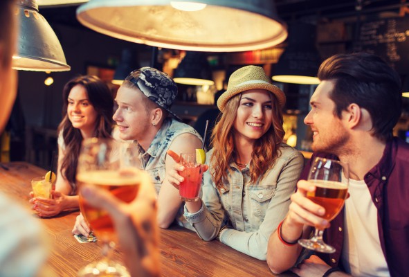 happy friends with drinks talking at bar or pub